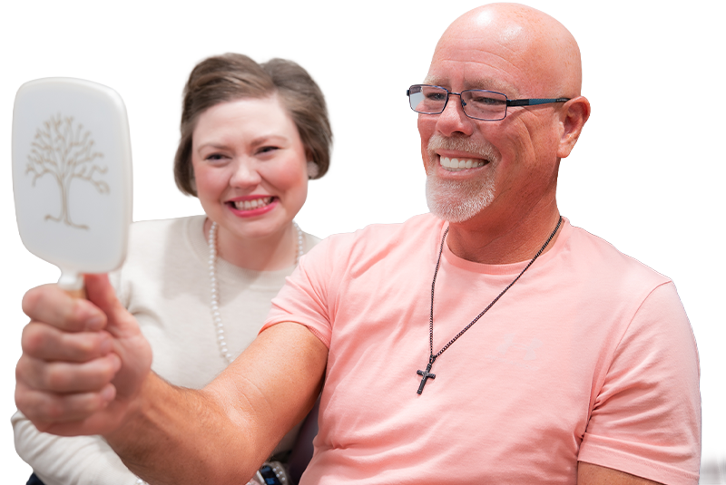 patient holding a mirror with staff member and smiling